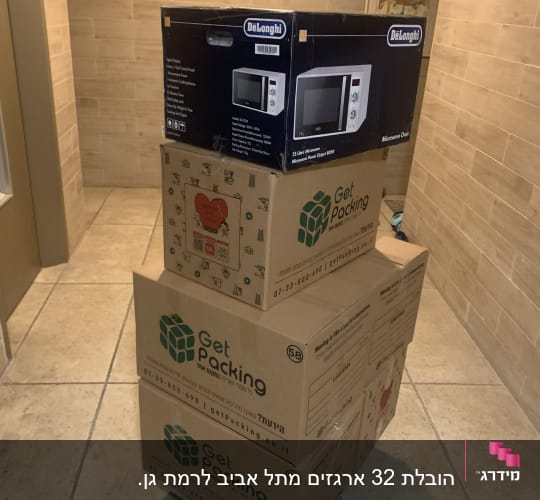 ארגזים עם מוצרי אריזה ומיקרוגל על עגלה